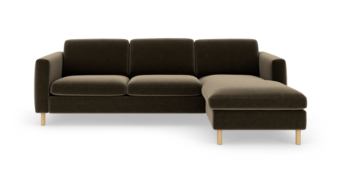 Mørkebrun 3-personers sofa med chaiselong til højre og lyse træben, frilagt på hvid baggrund.