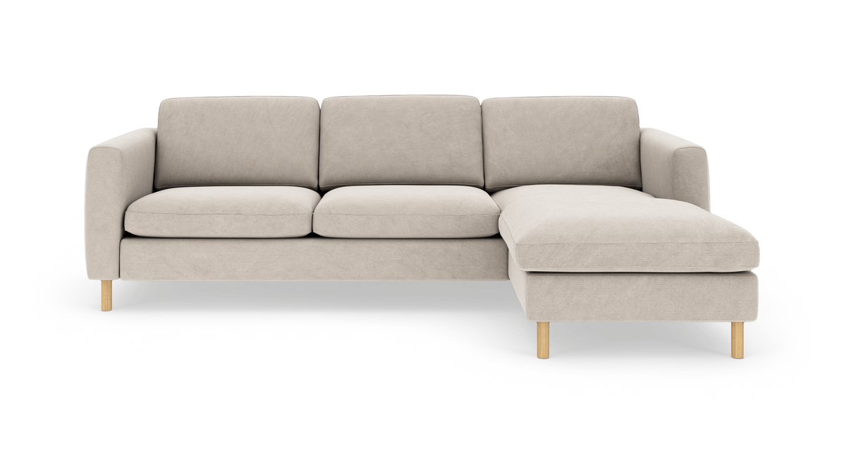 Beige hjørnesofa med højre chaiselong og lyse træben, set forfra mod hvid baggrund.