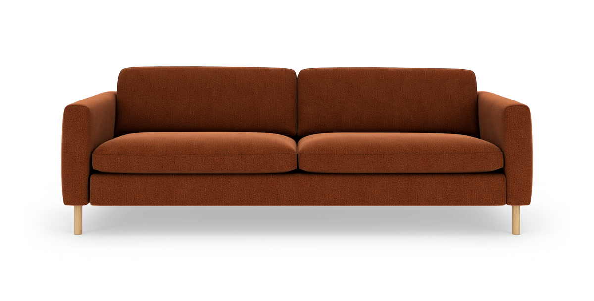 Rustrød tresæders sofa med afrundede armlæn og lyse træben, fotograferet lige forfra.