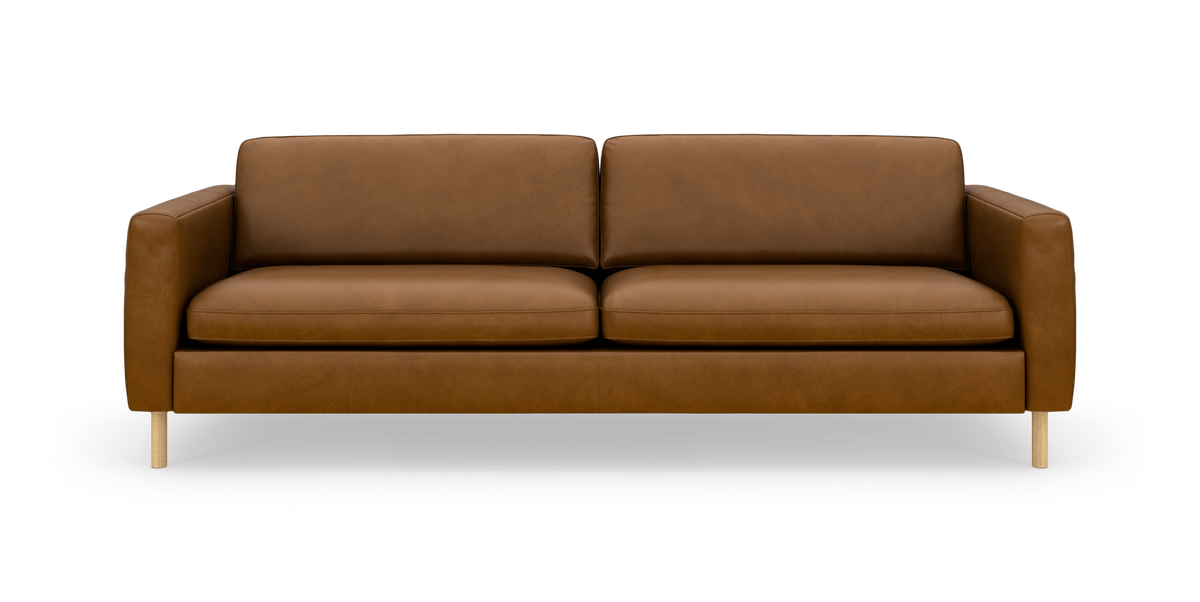 Brun lædersofa med to sædehynder og to ryghynder på træben, fotograferet lige for mod hvid studiobaggrund.