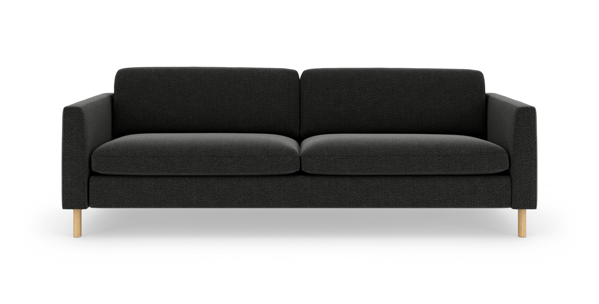 Mørkegrå 3-personers sofa med lige armlæn og lyse træben, to sæde- og ryghynder, fotograferet forfra mod hvid baggrund.