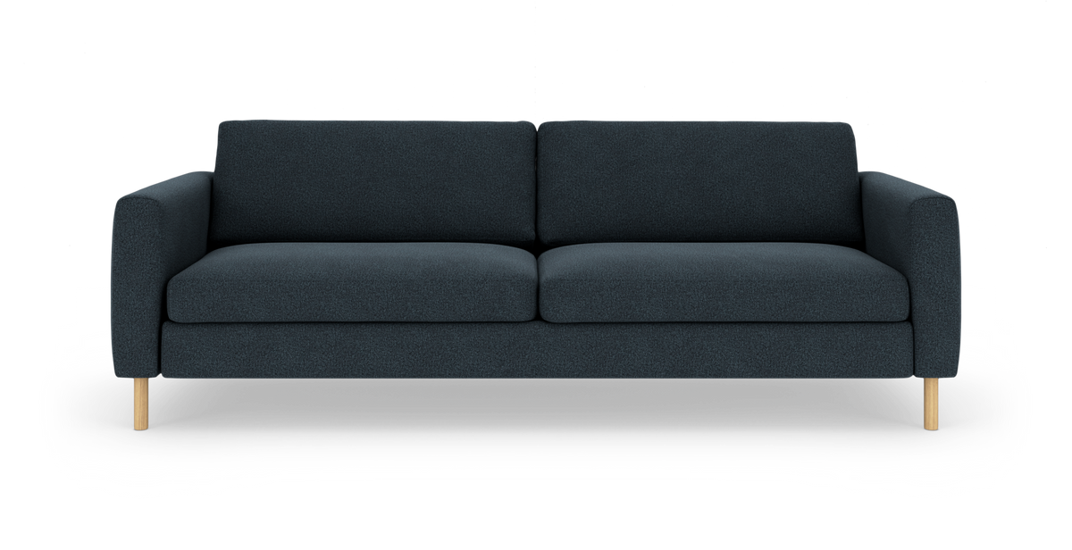 Mørk blågrå tresædet sofa med to sæde- og ryghynder samt lyse træben, fotograferet forfra mod hvid studiobaggrund.