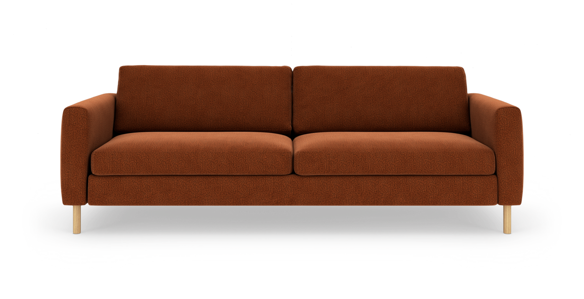 Rustfarvet trepersoners sofa med lige armlæn og lyse træben, frilagt på hvid baggrund.