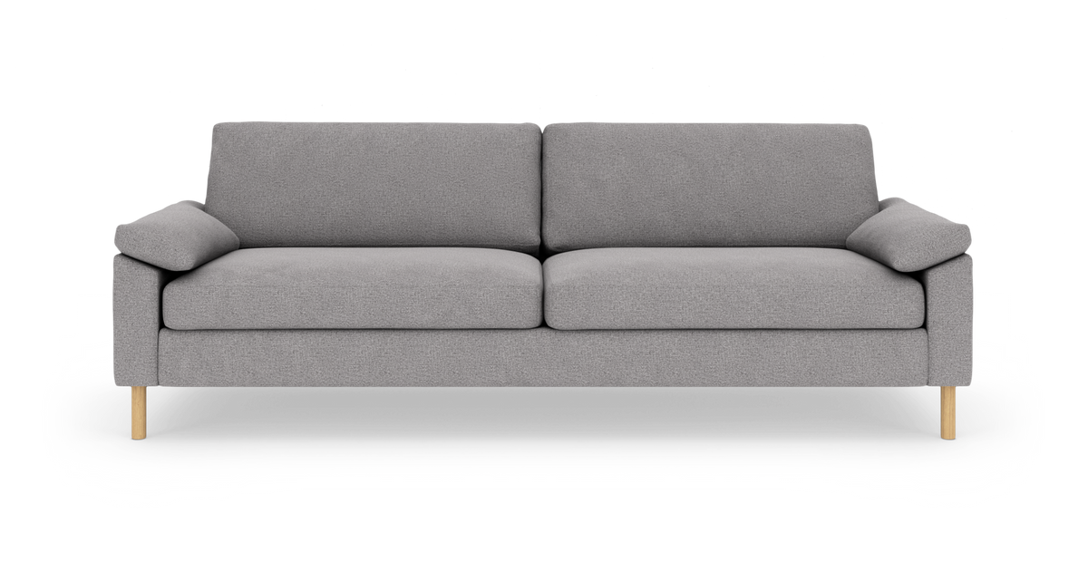 Grå tresæders sofa med bløde hynder og lyse træben, fotograferet forfra på hvid baggrund.