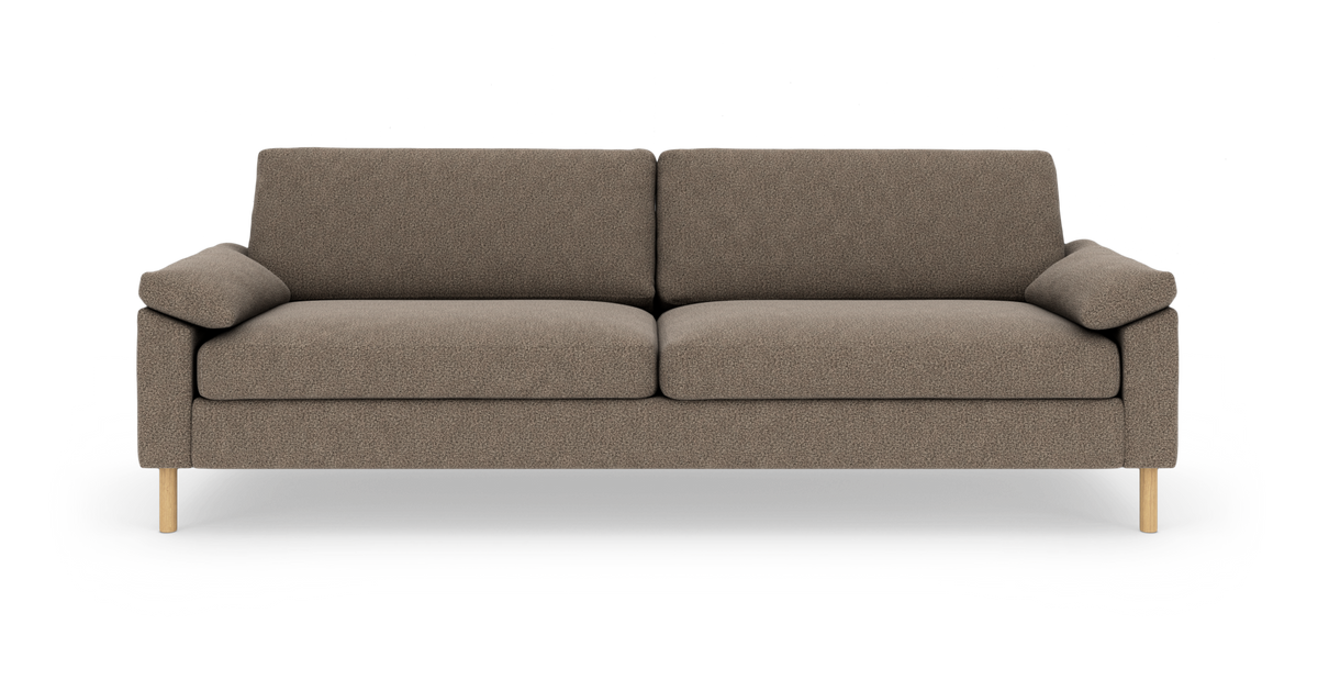 Brunmeleret 3-personers sofa med enkle linjer, løse ryg- og sædehynder og lyse træben, fotograferet lige for mod hvid baggrund.