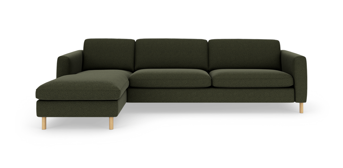Mørkegrøn modulsofa med venstrevendt chaiselong og lyse træben, set lige for i studiemiljø.