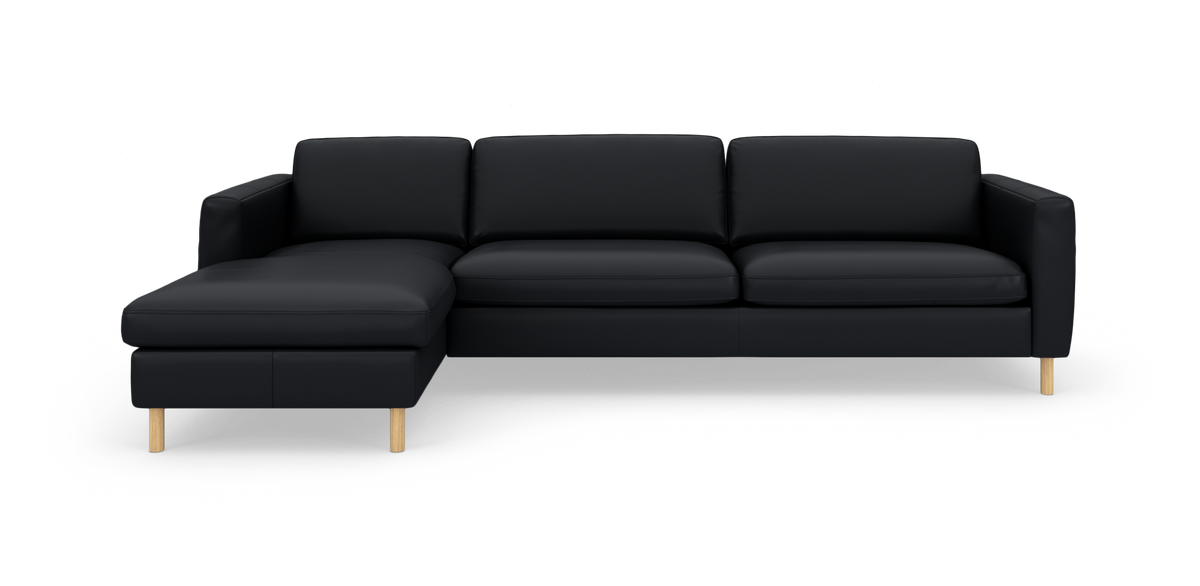 Sort hjørnesofa med venstrevendt chaiselong og lyse træben, fotograferet forfra mod hvid studiebaggrund.