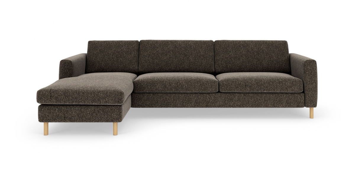 Brun stofhjørnesofa med venstre chaiselong og lyse træben, frontvisning mod hvid baggrund.
