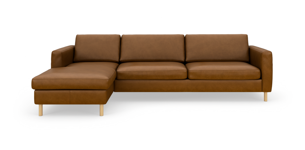 Brun hjørnesofa med venstrevendt chaiselong i læder, lige armlæn og lyse træben, frilagt på hvid baggrund.