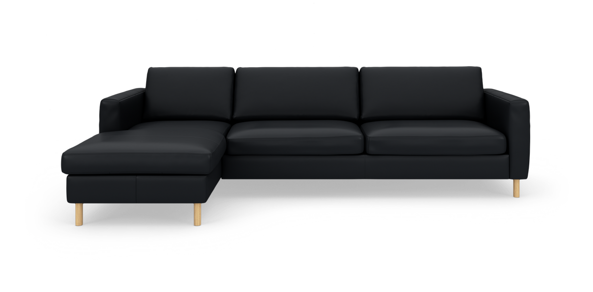 Sort modulsofa med venstrevendt chaiselong og lyse træben på hvid baggrund.