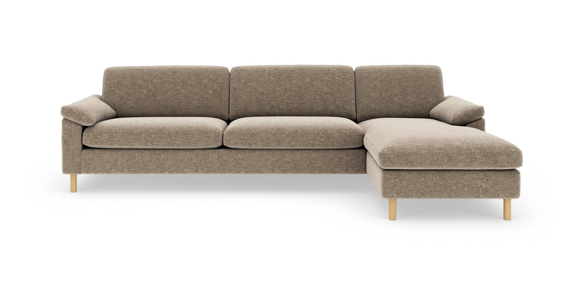 Beige hjørnesofa med chaiselong til højre, træben og blød stofpolstring i studiemiljø.