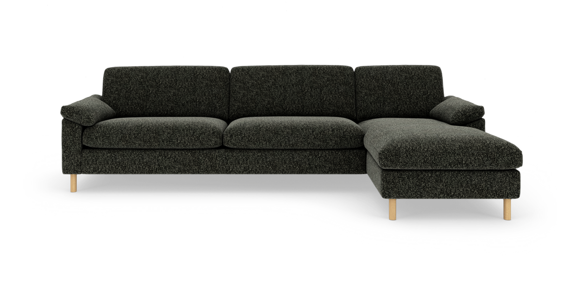 Mørkegrå hjørnesofa med chaiselong til højre og lyse træben, frilagt på hvid baggrund.