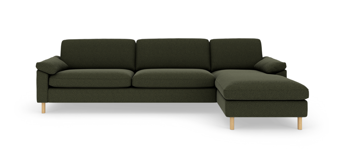 Mørkegrøn hjørnesofa med chaiselong til højre og lyse træben, frilagt mod hvid baggrund.
