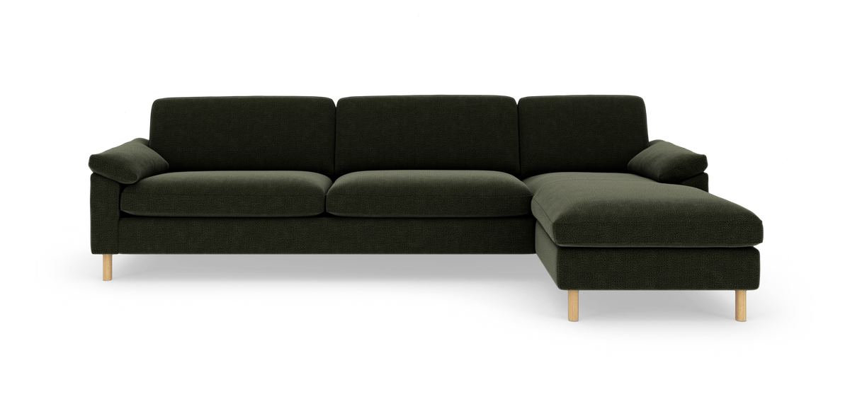 Mørkegrøn hjørnesofa med chaiselong til højre og lyse træben, frilagt på hvid baggrund.