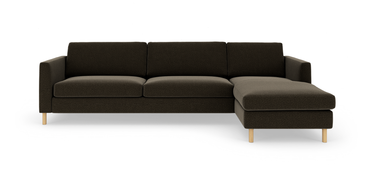 Mørkebrun hjørnesofa med højre chaiselong på lys studiobaggrund og lyse træben.