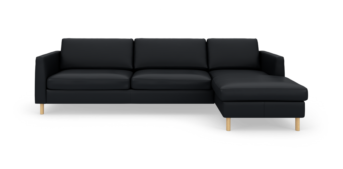 Sort L‑sofa med højre chaiselong og lyse træben, fotograferet forfra på hvid baggrund.