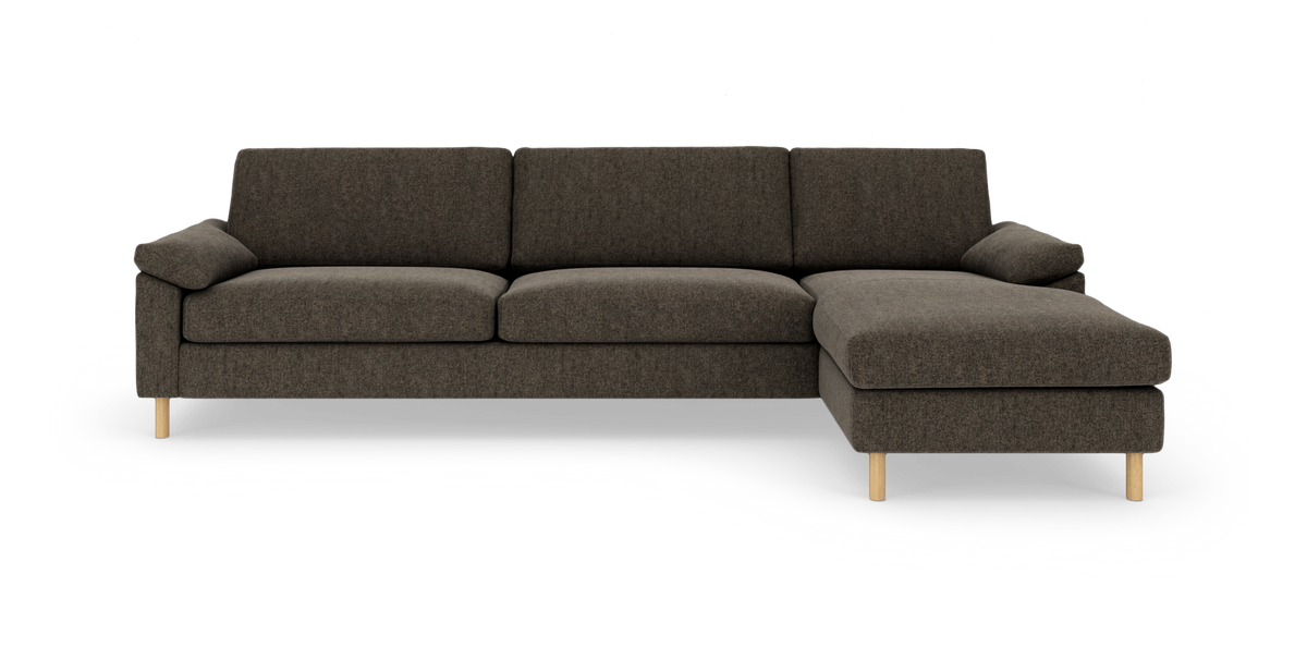 Mørkegrå modulsofa med chaiselong til højre og lyse træben, frilagt på hvid baggrund.