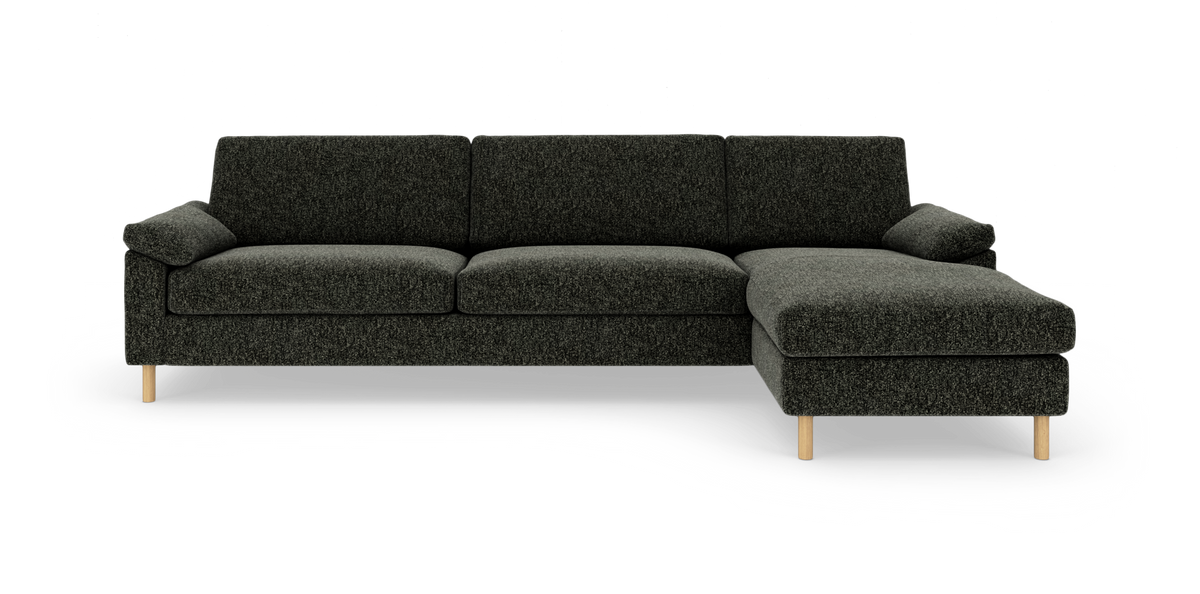 Mørkegrå modulsofa med højre chaiselong og lyse træben, frilagt på hvid baggrund.