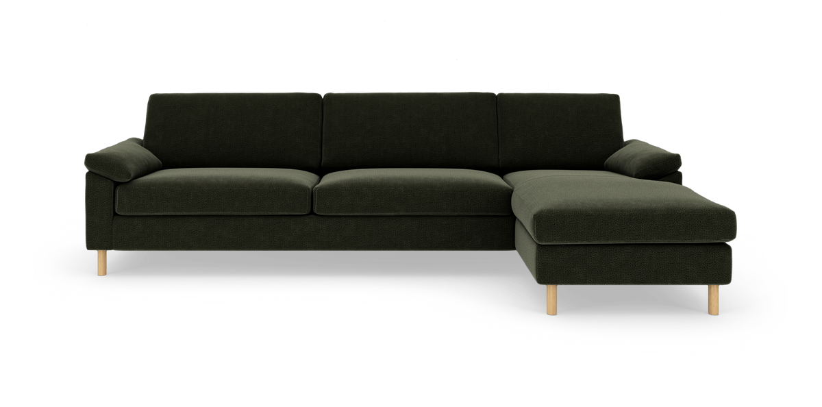 Mørkegrøn L‑sofa med højre chaiselong og lyse træben, fritlagt på hvid baggrund.