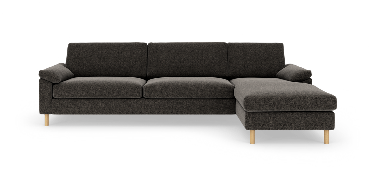Mørkegrå hjørnesofa med chaiselong til højre og runde træben, set forfra mod hvid baggrund.