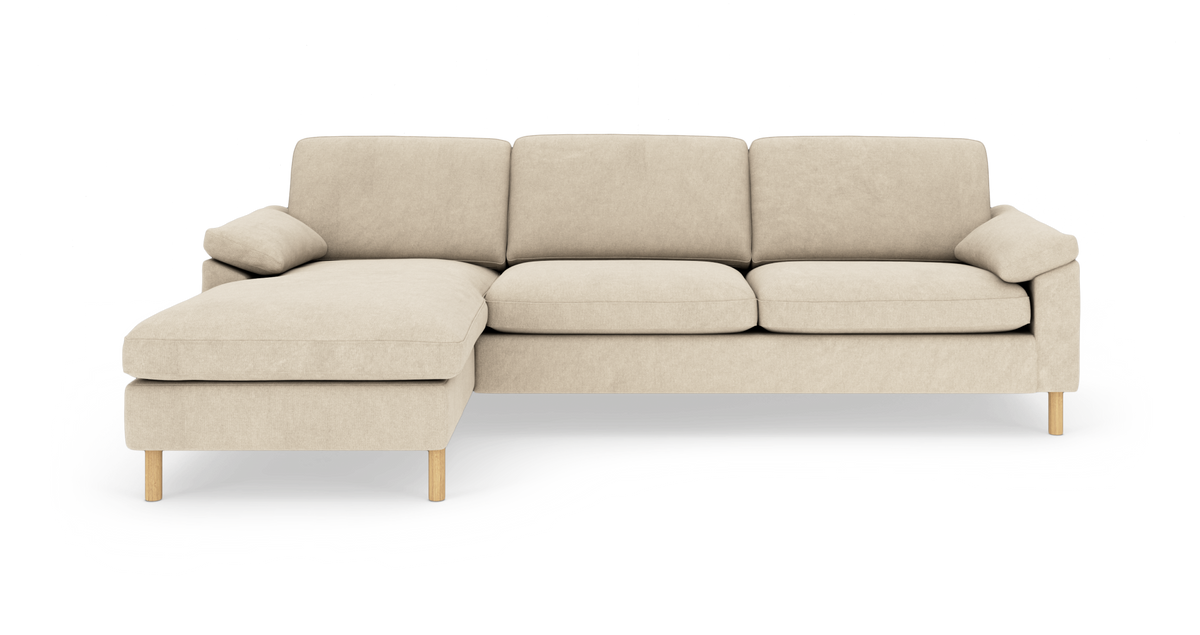 Beige modulsofa med venstre chaiselong, tre sædehynder og lyse træben i studieopsætning.