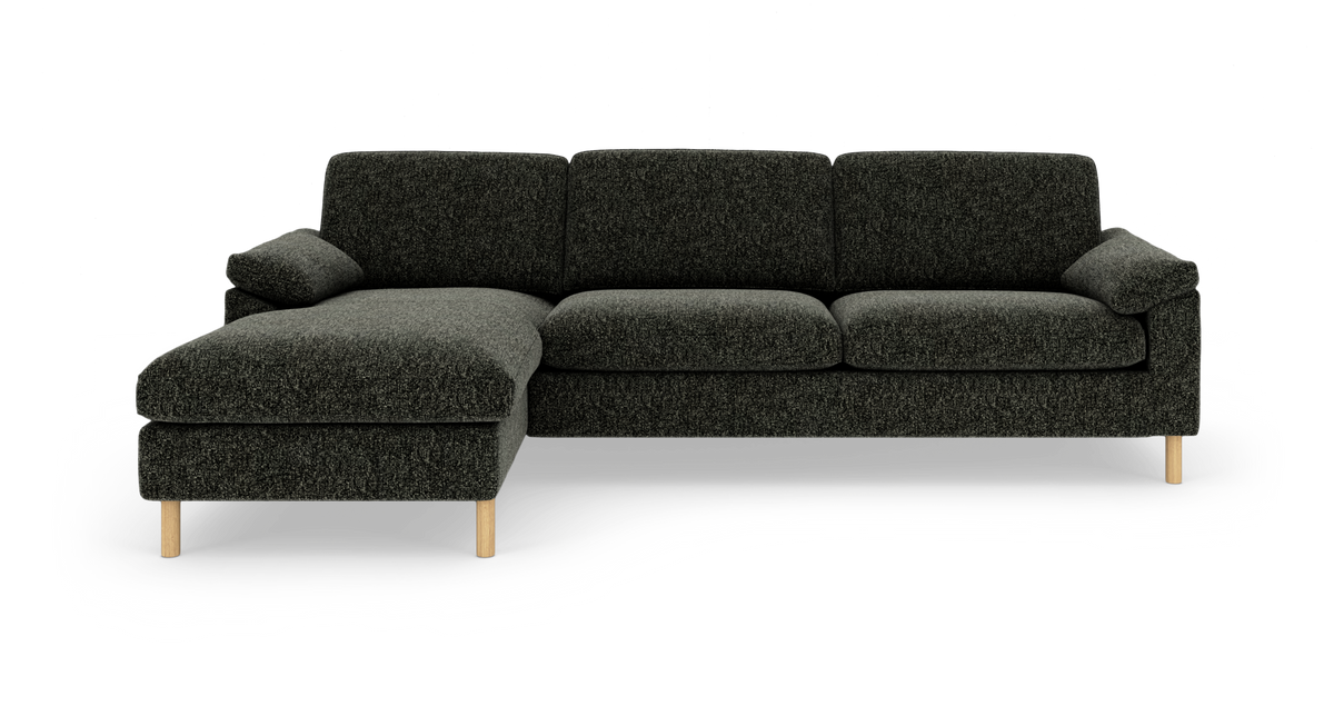 Mørkegrå stofsofa med venstrevendt chaiselong og lyse træben, frilagt på hvid baggrund.