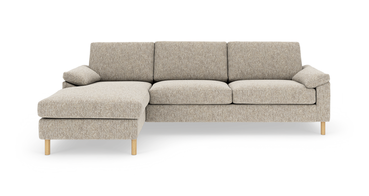 Beige hjørnesofa med venstrevendt chaiselong og lyse træben, fotograferet i studie.