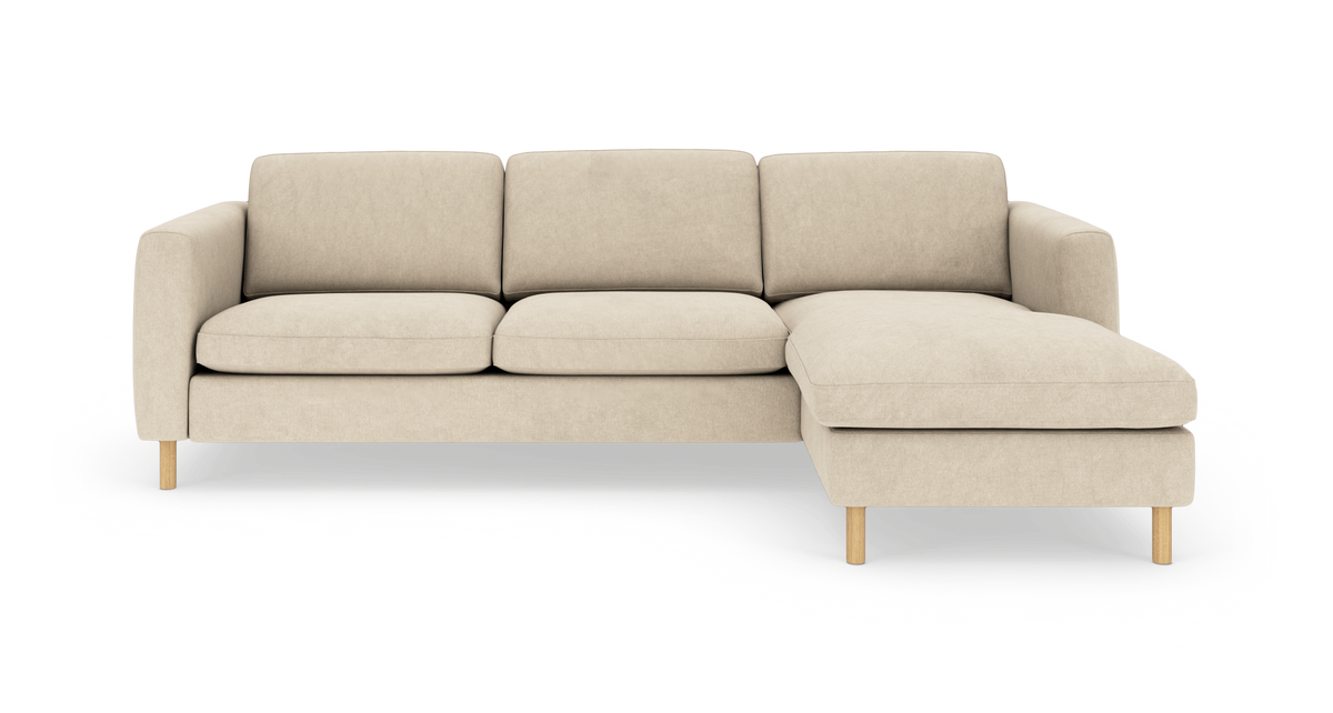 Beige hjørnesofa med højre chaiselong på slanke træben, fotograferet lige for mod hvid baggrund.