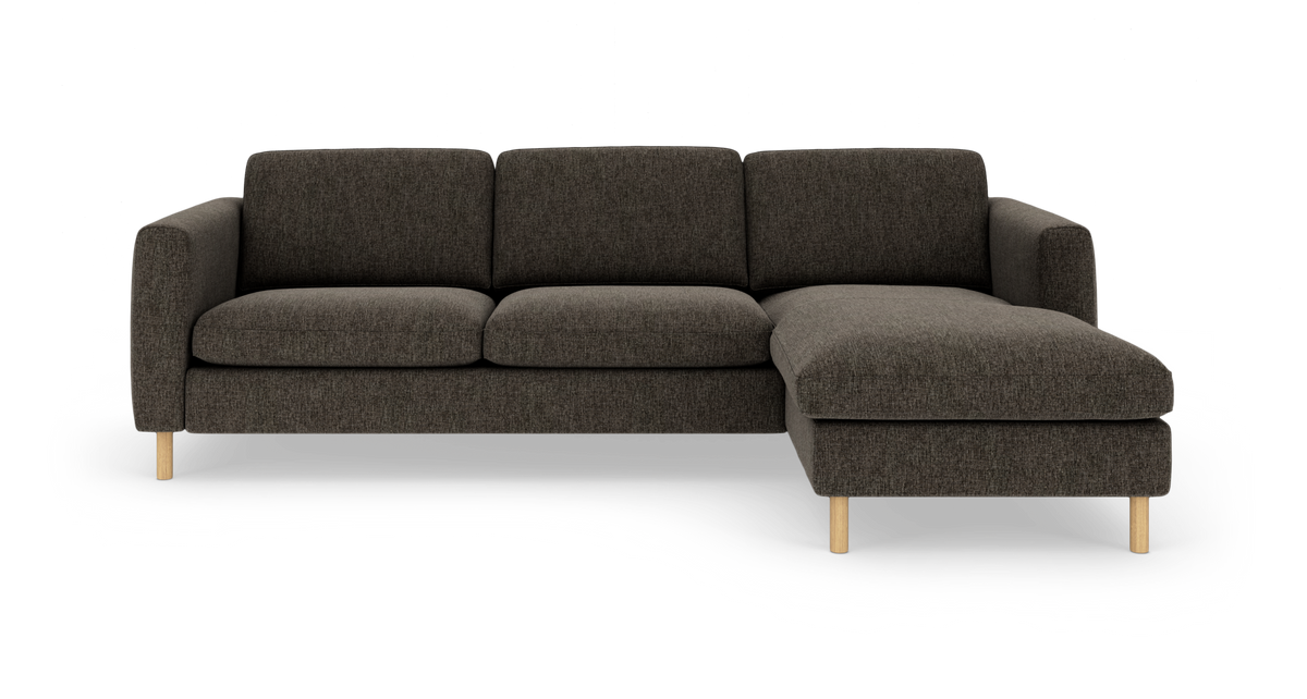 Mørkegrå L-formet sofa med højre vendt chaiselong og lyse træben på hvid baggrund.
