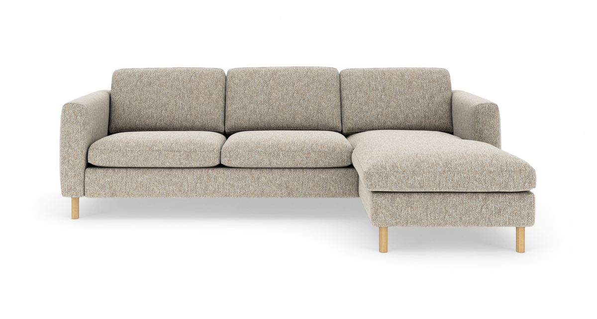 Beigefarvet tresæders sofa med chaiselong på højre side, polstret stof og lyse træben, frilagt på hvid baggrund.