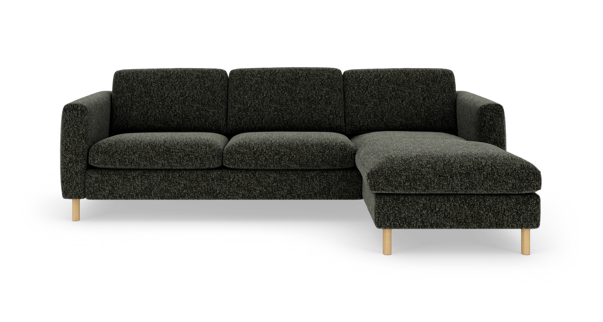 Mørkegrå hjørnesofa med chaiselong til højre og lyse træben, frilagt på hvid baggrund.