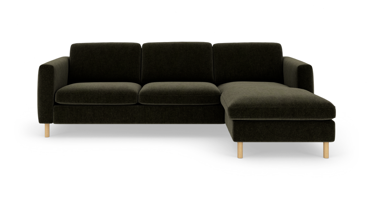 Mørkegrøn tresædet sofa med chaiselong til højre, polstret i stof og med lyse træben, frilagt på hvid baggrund.