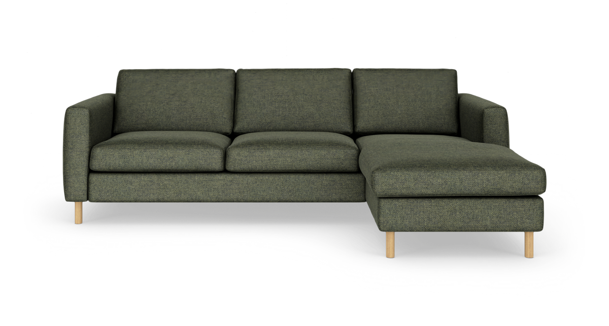 Grøn hjørnesofa med højre chaiselong, tre sædehynder og lyse træben, fotograferet lige for mod hvid baggrund.