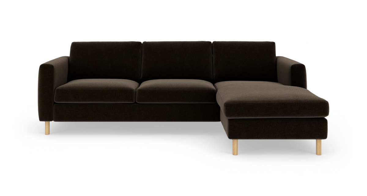 Mørkebrun hjørnesofa med chaiselong til højre, rene linjer og lyse træben, frilagt på hvid baggrund.