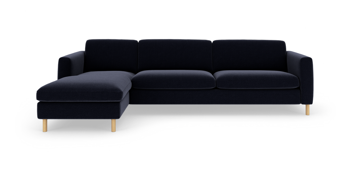 Mørkeblå hjørnesofa med venstrevendt chaiselong og lyse træben, frilagt mod hvid baggrund.