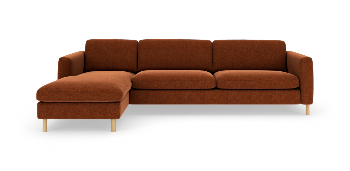 Hjørnesofa med venstre chaiselong i rustfarvet stof, runde træben og tre ryghynder, fritlagt mod hvid baggrund.