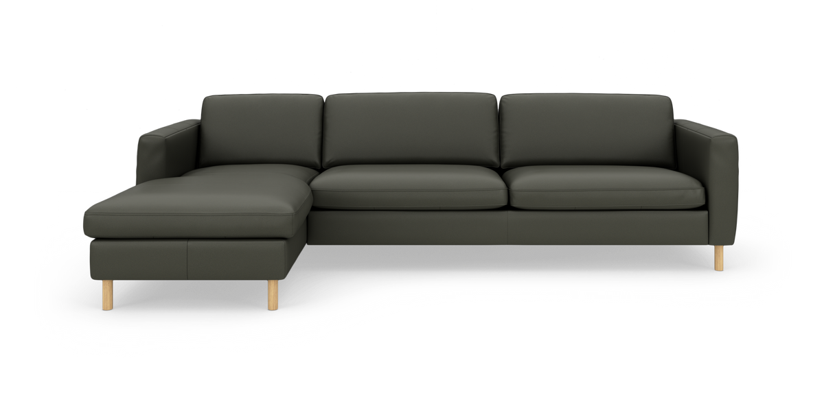 Mørkegrøn hjørnesofa med venstre chaiselong og lyse træben, fritstående mod hvid baggrund.
