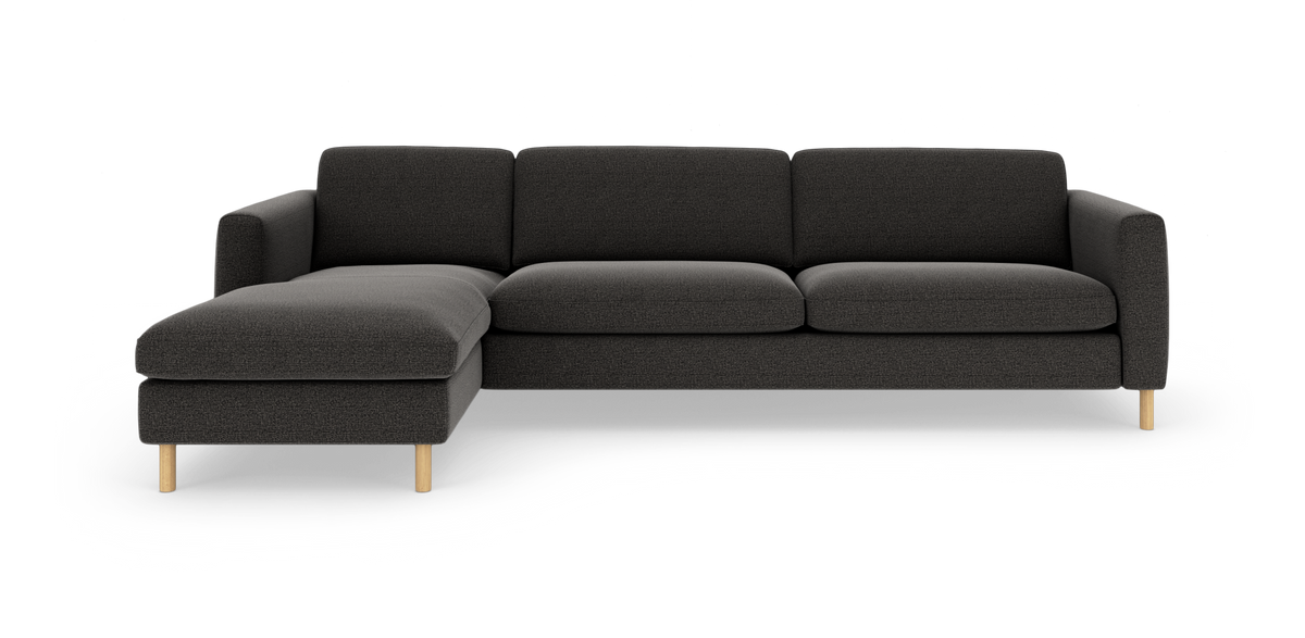 Mørkegrå L‑sofa med venstre chaiselong og lyse træben, fritstående på hvid baggrund.