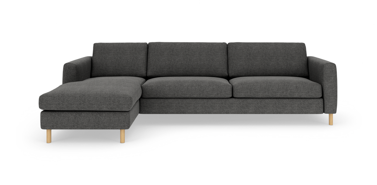 Mørkegrå modulsofa med venstrevendt chaiselong, slanke armlæn og lyse træben på hvid studiobaggrund.