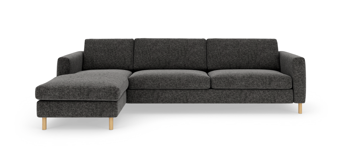 Mørkegrå modulsofa med venstrevendt chaiselong og lyse træben, frontal produktvisning.