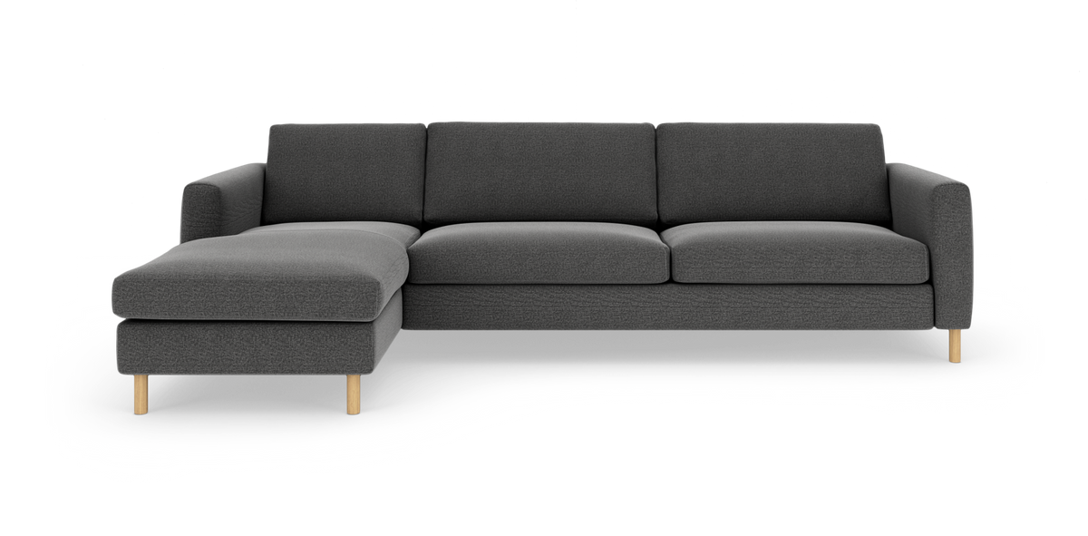 Mørkegrå tresædet hjørnesofa med venstrevendt chaiselong og lyse træben, frilagt på hvid baggrund.