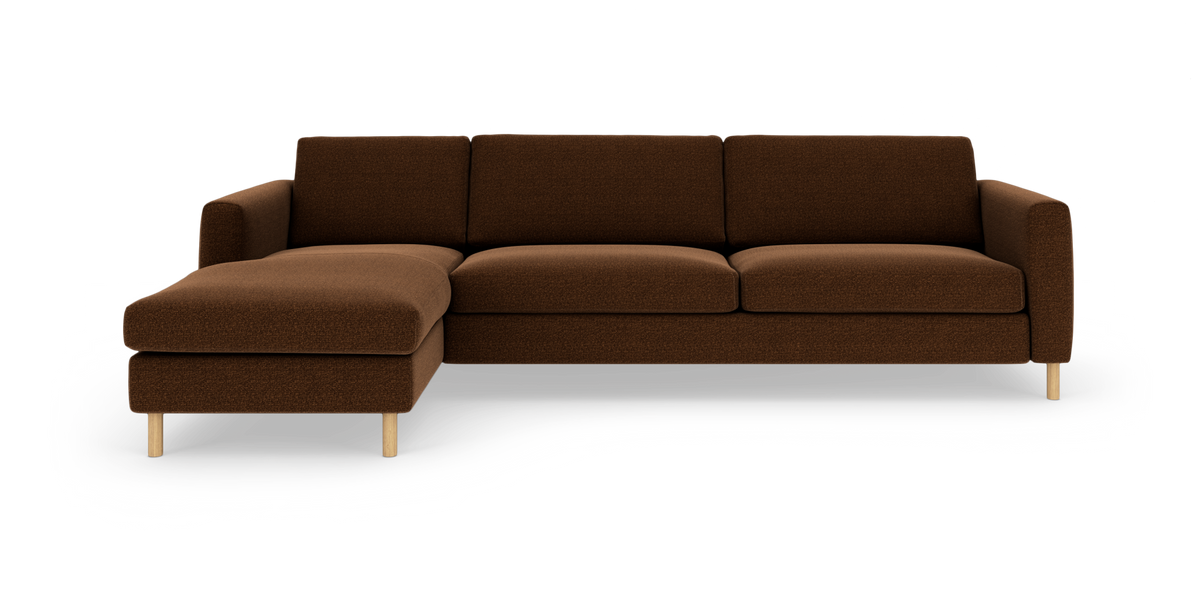 Brun hjørnesofa med venstrevendt chaiselong, stofbetrukket med lyse træben, frilagt på hvid baggrund.