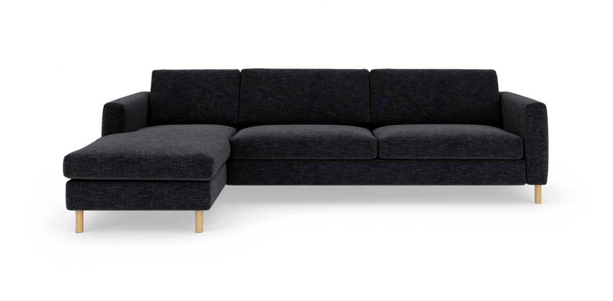 Mørkegrå hjørnesofa med venstrevendt chaiselong og lyse træben, fritlagt på hvid baggrund.