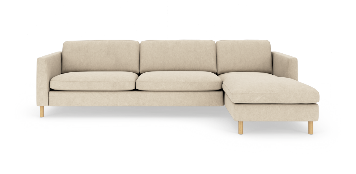 Beige hjørnesofa med chaiselong til højre og lyse træben i moderne, minimalistisk design.