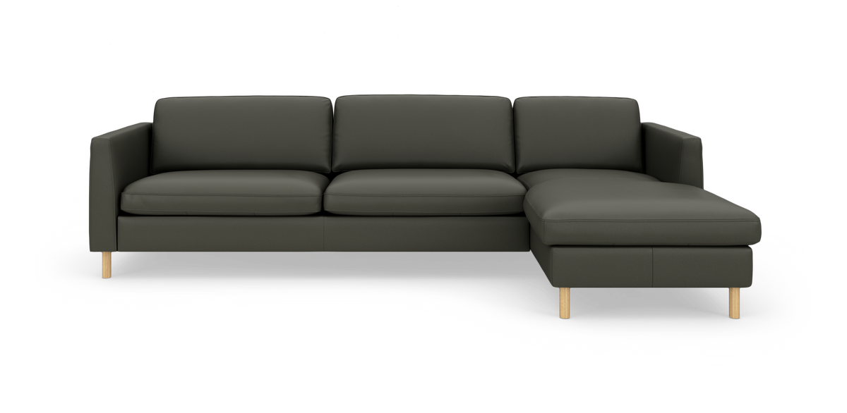 Mørkegrøn hjørnesofa med chaiselong til højre og lyse træben, moderne minimalistisk, frilagt på hvid baggrund.