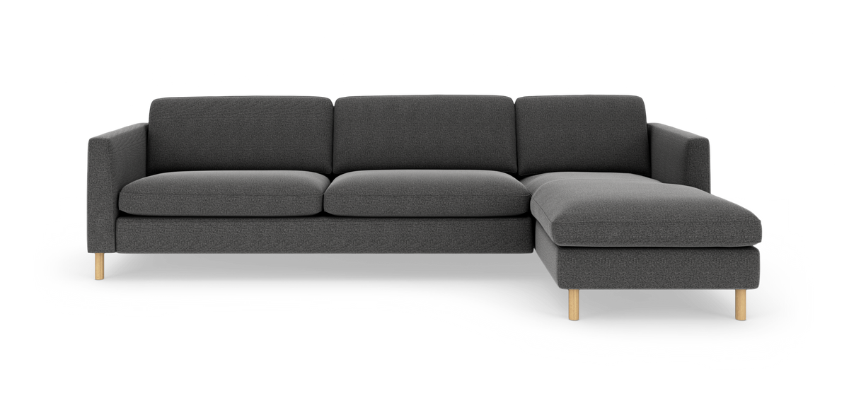 Mørkegrå sofa med chaiselong til højre og lyse træben, frontvisning i studieopsætning.