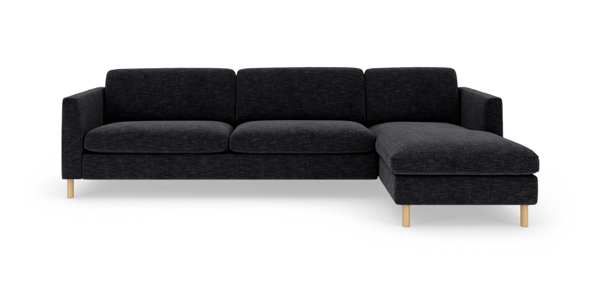 Mørkegrå hjørnesofa med chaiselong til højre og lyse træben på hvid baggrund.
