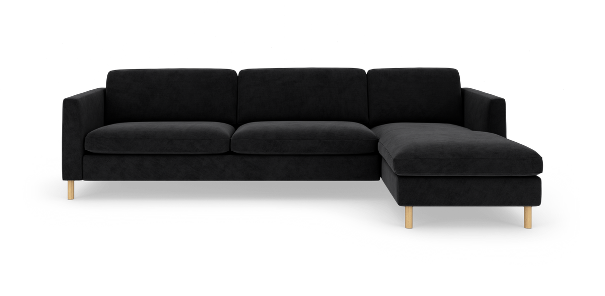 Sort hjørnesofa med chaiselong til højre og lyse træben på hvid baggrund.
