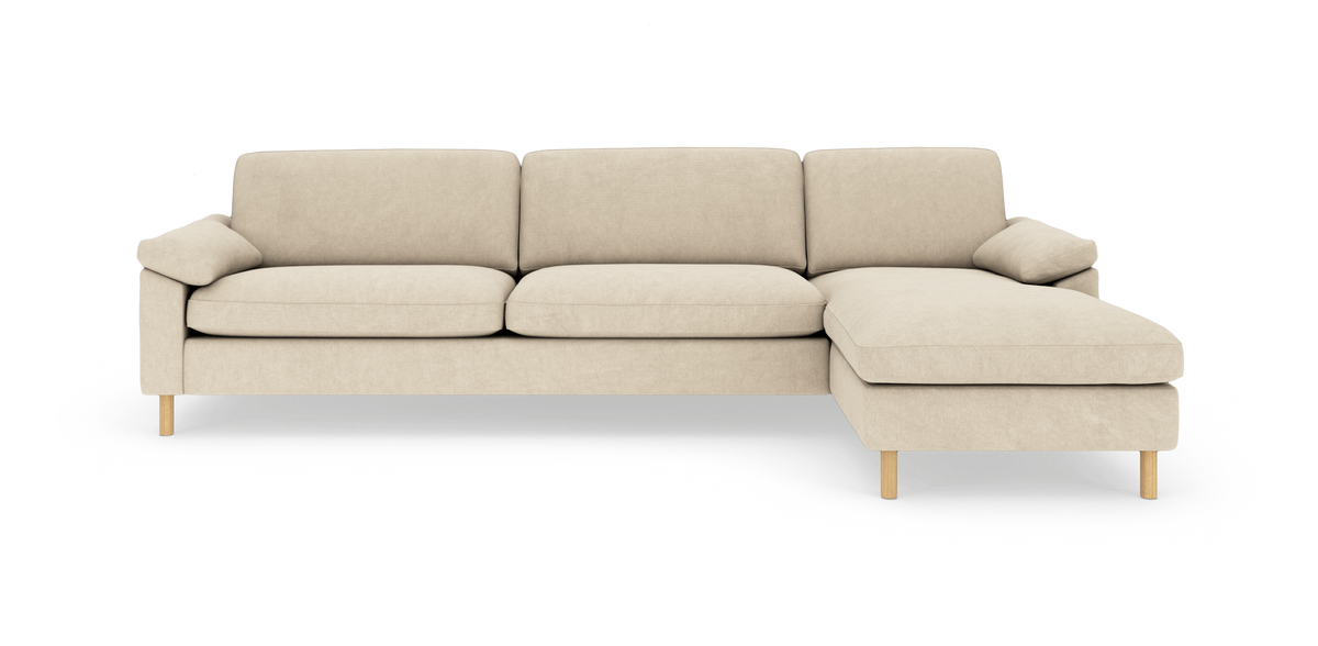 Beige hjørnesofa med chaiselong til højre, rene linjer og træben, frilagt på hvid baggrund.