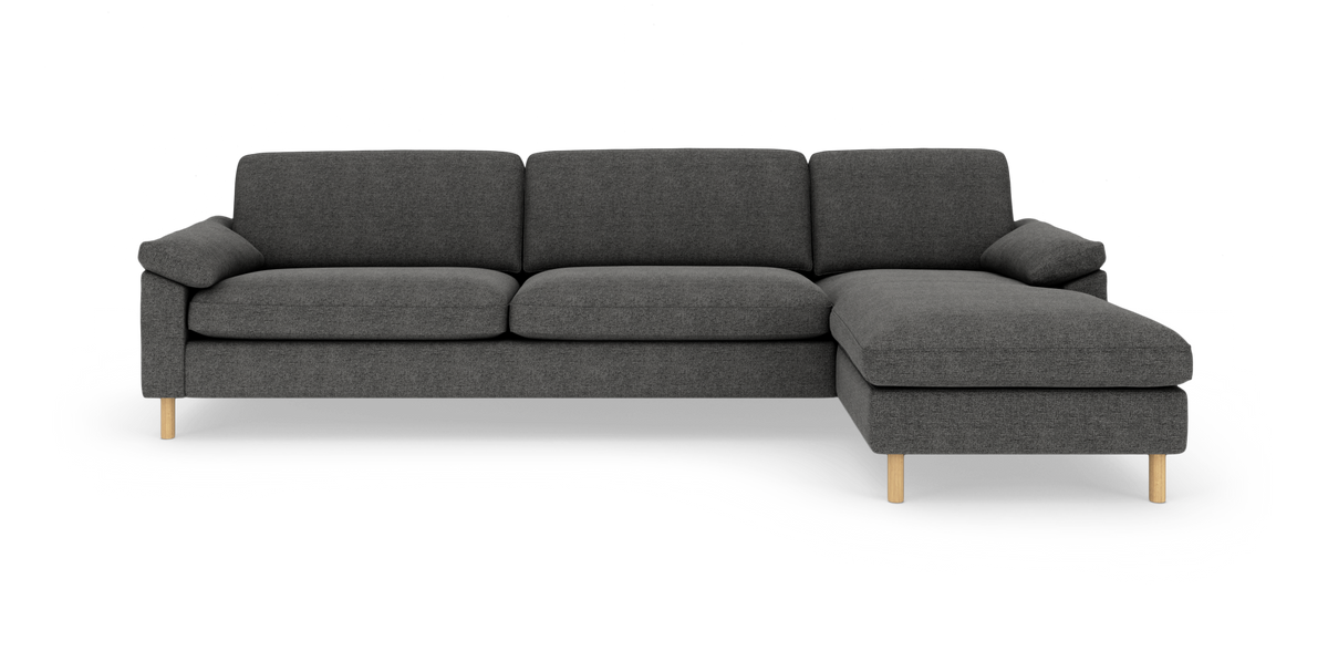 Mørkegrå hjørnesofa med chaiselong til højre på hvid baggrund, med lyse træben.